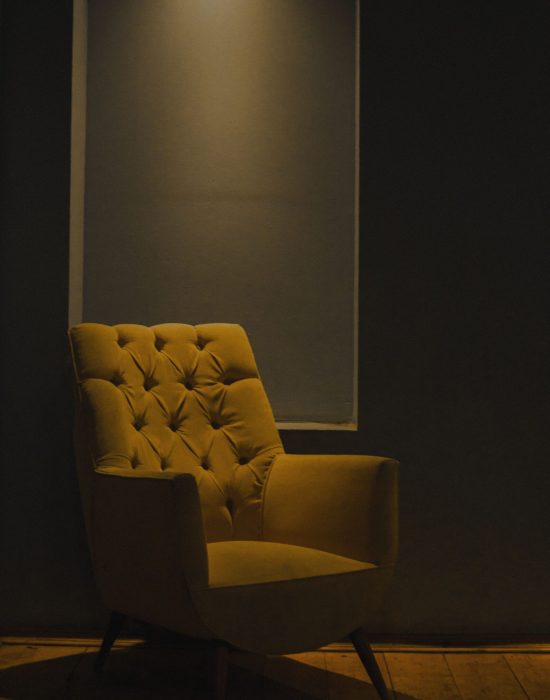 A stylish yellow chair in a dimly lit minimalist room creates a cozy ambiance.